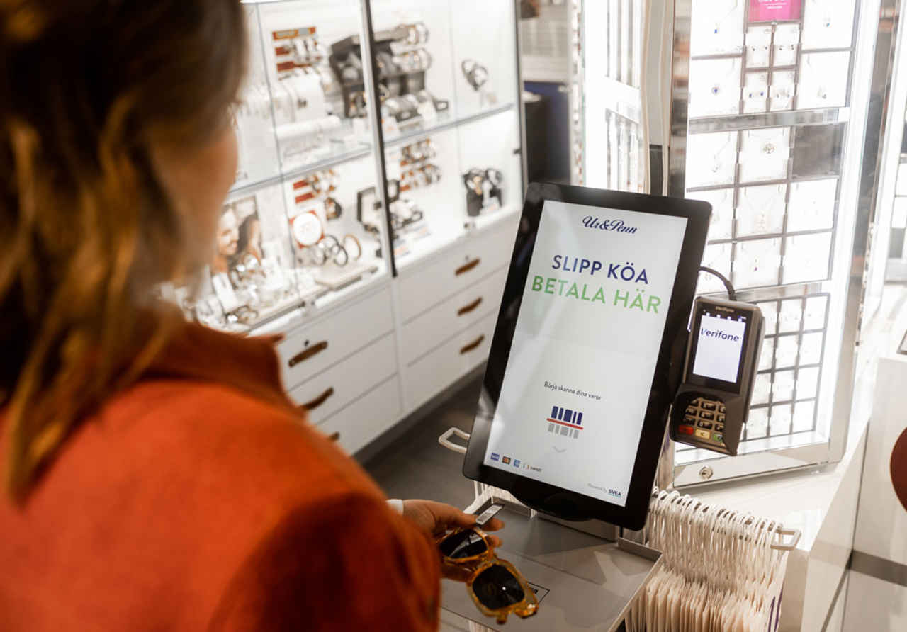 Kvinna som betalar i självbetjäningskassa i butik