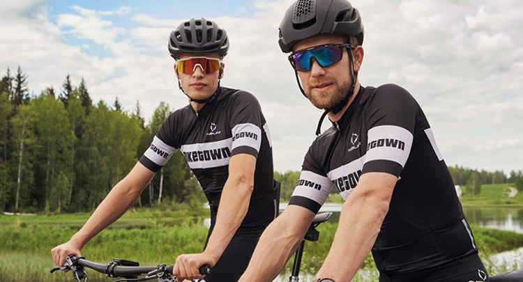 Två tävlingscyklister med hjälpar och skyddsglasögon