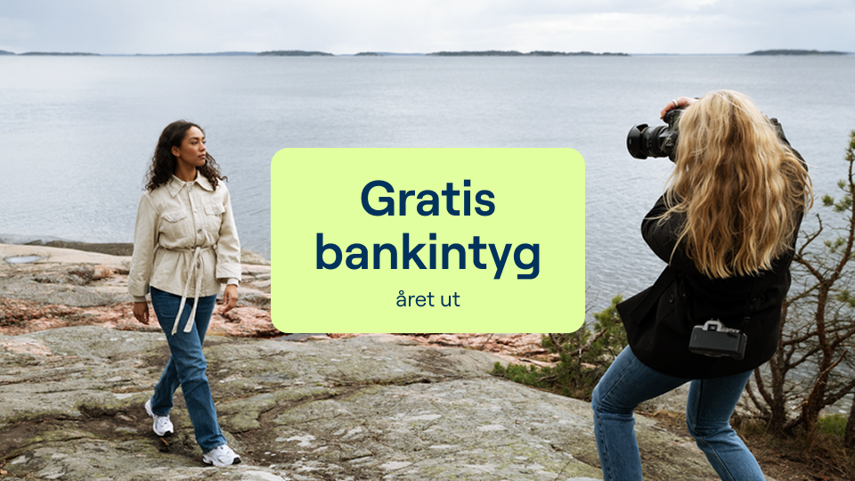 Två kvinnor som fotograferar varandra på en klippa vid havet