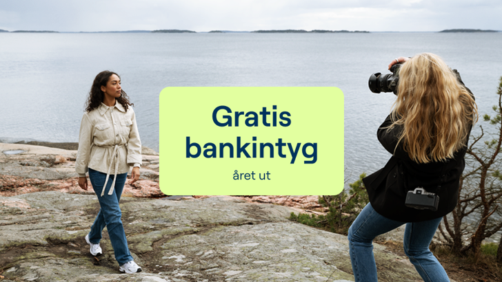 Två kvinnor som fotograferar varandra på en klippa vid havet