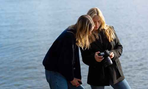 Två tjejer som fotograferar vid havet