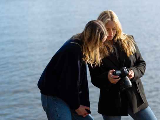 Två tjejer som fotograferar vid havet
