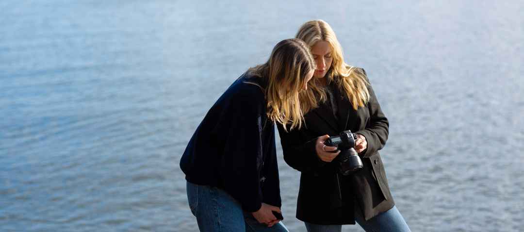 Två tjejer som fotograferar vid havet