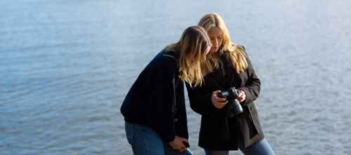 Två tjejer som fotograferar vid havet