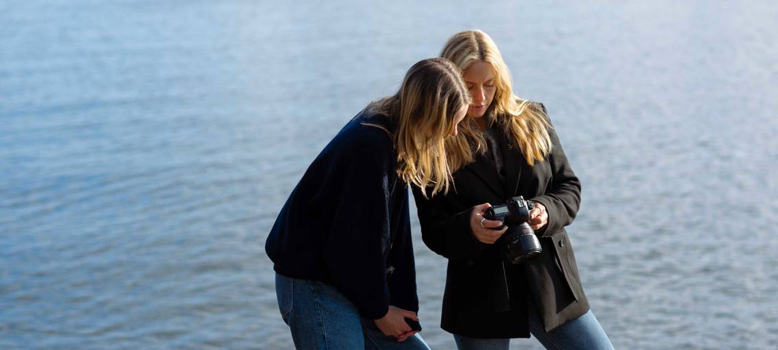 Två tjejer som fotograferar vid havet