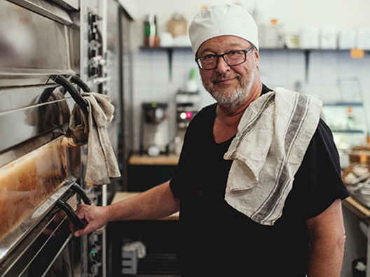 Äldre man i kockmössa i restaurangkök