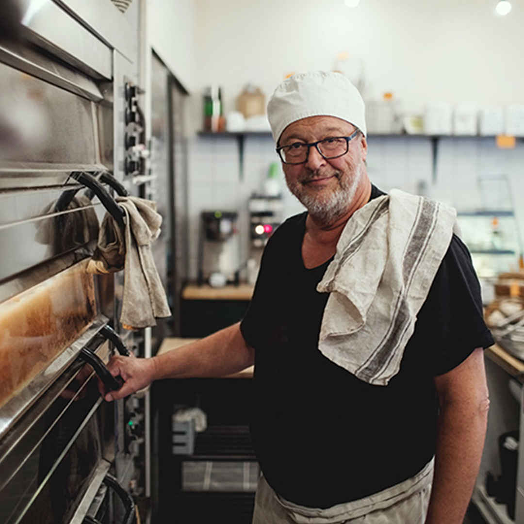 Äldre man i kockmössa i restaurangkök