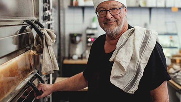 Äldre man i kockmössa i restaurangkök