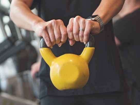 Händer som håller i en gul kettle bell