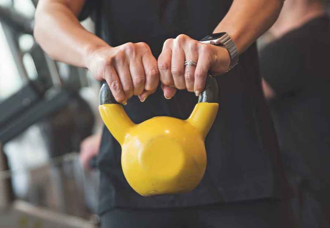 Händer som håller i en gul kettle bell