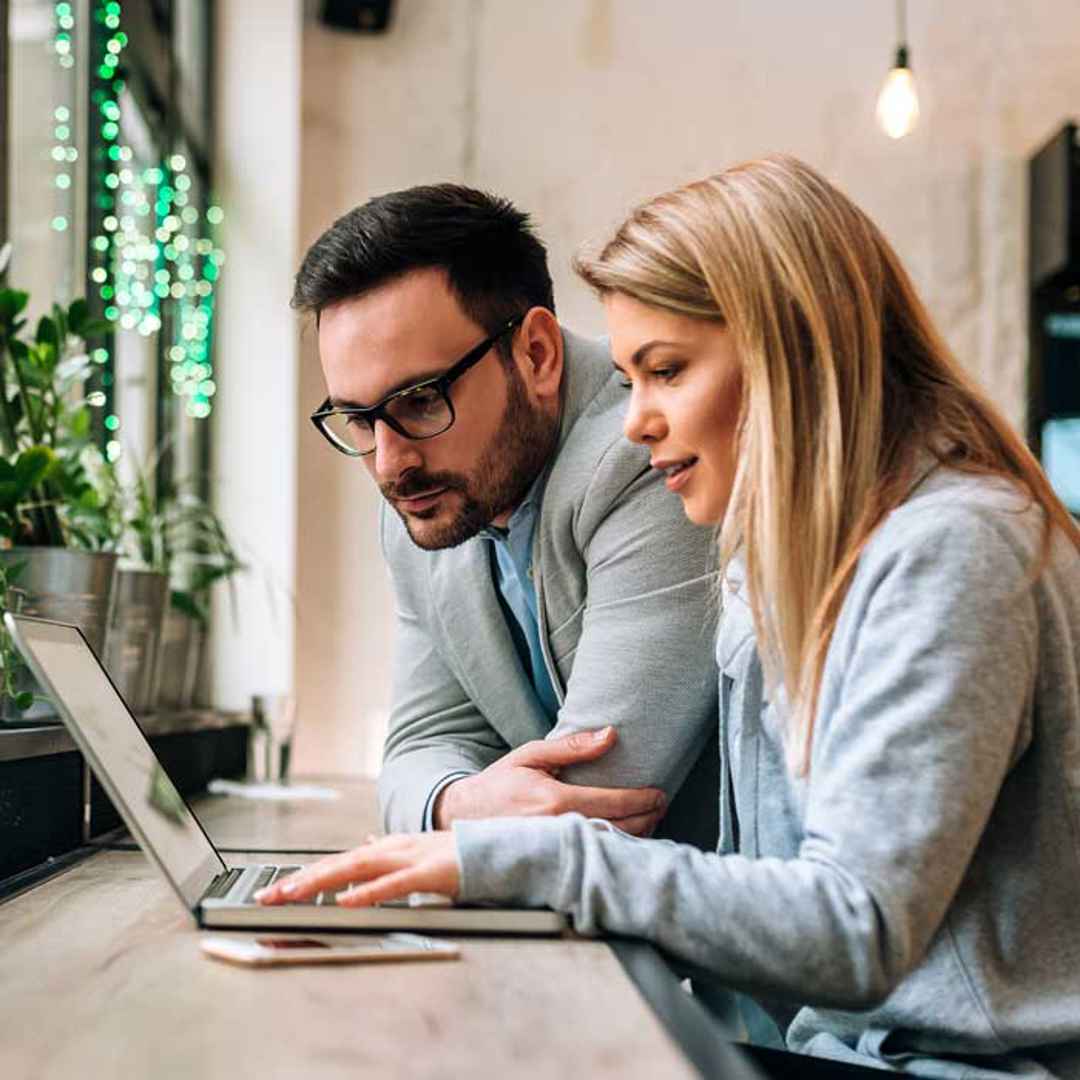 Man och kvinna sitter vid ett fönsterbord och tittar i en laptop