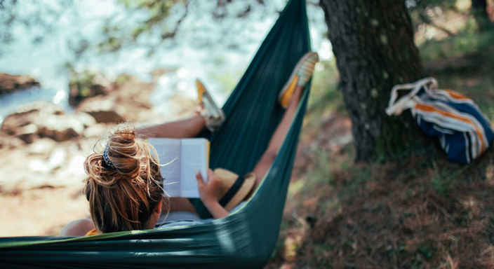 Kvinna läser bok i hängmatta