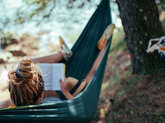 Kvinna läser bok i hängmatta
