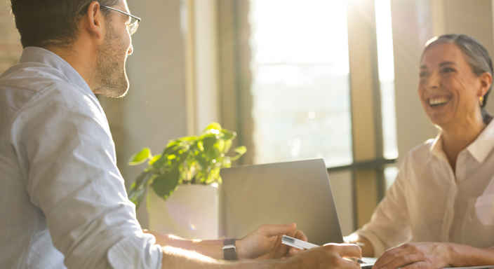 Man och kvinna samtalar vid ett skrivbord