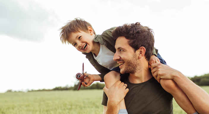 Pappa med barn på axlarna, leker utomhus