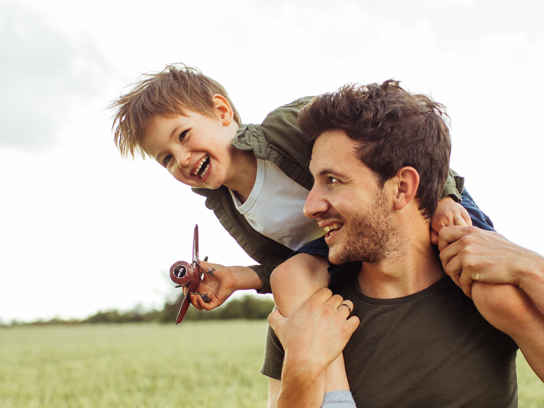 Pappa med barn på axlarna, leker utomhus