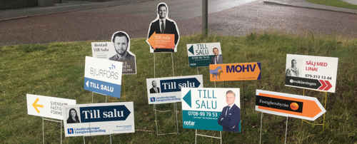 Till-salu-skyltar från mäklare i en gräsmatta